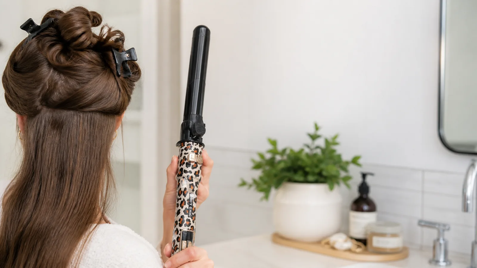 Beginner preparing sectioned dry hair before using an automatic rotating hair curler in a UK bathroom